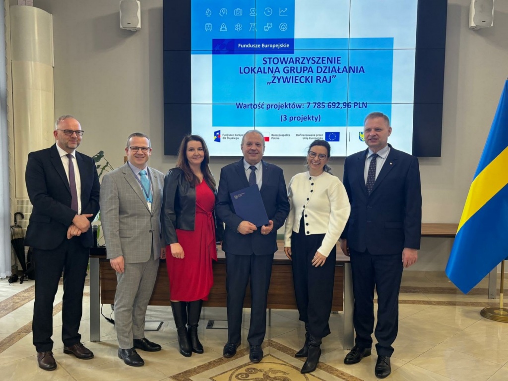 &bdquo;Zdjęcia dokumentujące uroczyste wręczenie List&oacute;w Gratulacyjnych w&nbsp;dniu 31 marca 2026 r.&nbsp;w&nbsp;Urzędzie Marszałkowskim w&nbsp;Katowicach. Na fotografiach przedstawiono przedstawicieli Stowarzyszenia &ndash; Lokalnej Grupy Działania &bdquo;Żywiecki Raj&rdquo; oraz uczestnik&oacute;w wydarzenia podczas wystąpienia, wręczenia dokument&oacute;w i&nbsp;wsp&oacute;lnego zdjęcia. W&nbsp;tle widoczny ekran prezentacyjny z&nbsp;informacją o&nbsp;projektach oraz flagi Polski i&nbsp;Unii Europejskiej.&rdquo;