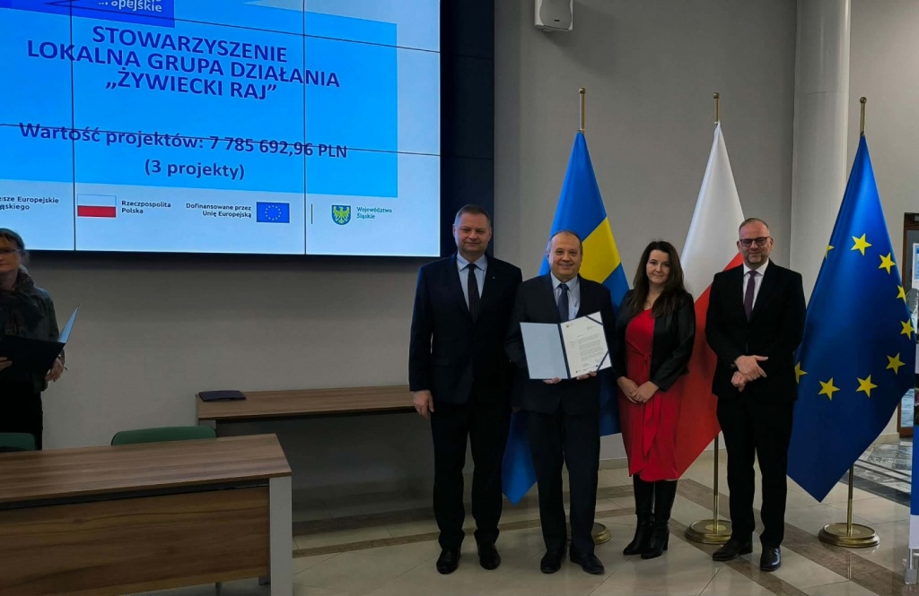 &bdquo;Zdjęcia dokumentujące uroczyste wręczenie List&oacute;w Gratulacyjnych w&nbsp;dniu 31 marca 2026 r.&nbsp;w&nbsp;Urzędzie Marszałkowskim w&nbsp;Katowicach. Na fotografiach przedstawiono przedstawicieli Stowarzyszenia &ndash; Lokalnej Grupy Działania &bdquo;Żywiecki Raj&rdquo; oraz uczestnik&oacute;w wydarzenia podczas wystąpienia, wręczenia dokument&oacute;w i&nbsp;wsp&oacute;lnego zdjęcia. W&nbsp;tle widoczny ekran prezentacyjny z&nbsp;informacją o&nbsp;projektach oraz flagi Polski i&nbsp;Unii Europejskiej.&rdquo;